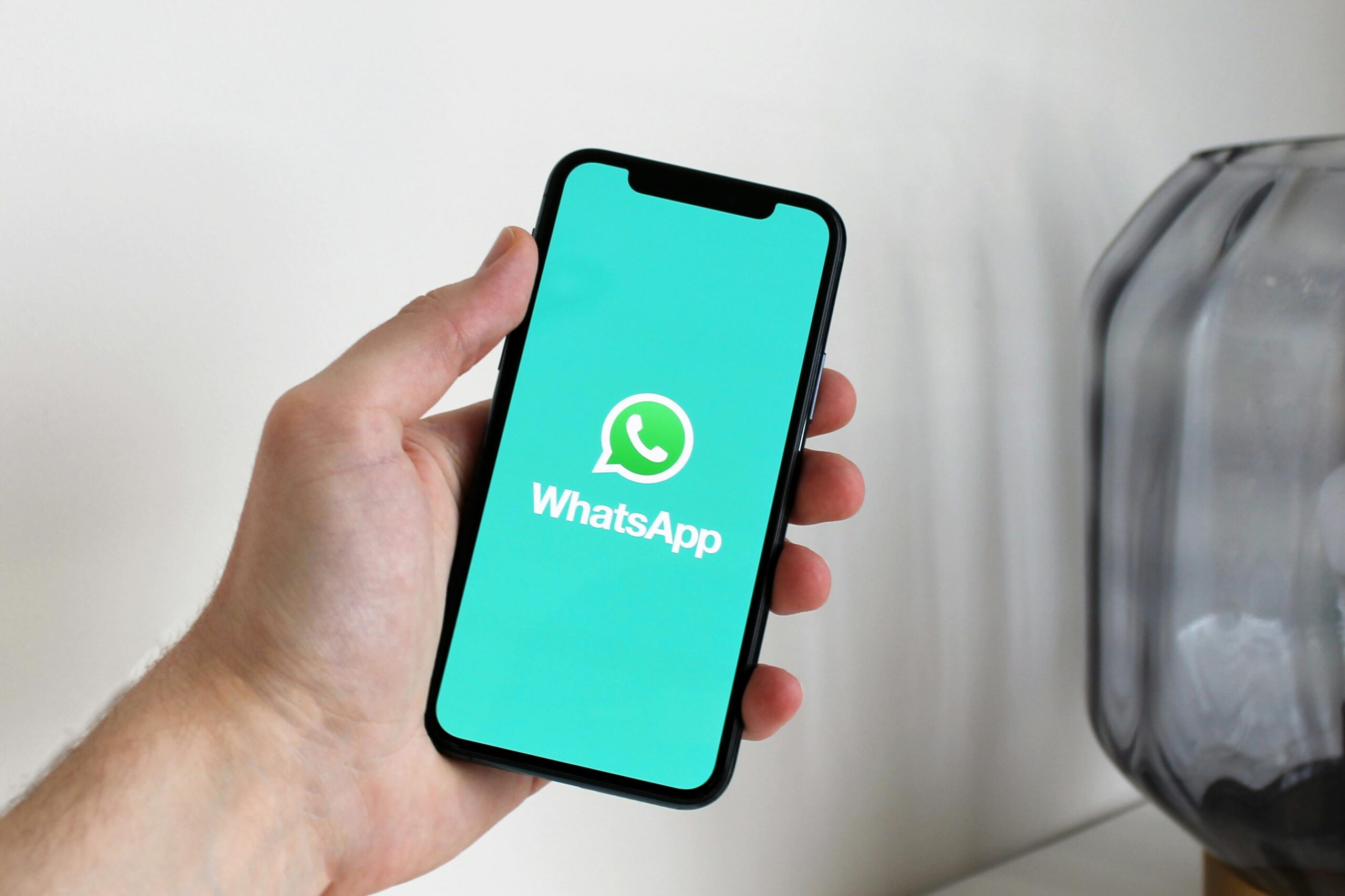 Primer plano de una mano que sostiene un teléfono inteligente que muestra la pantalla de la aplicación WhatsApp.